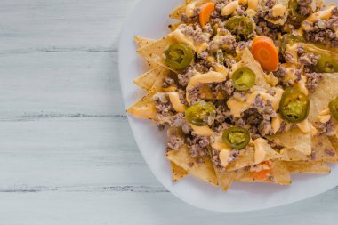 Nacho cips Mısır kıyma, eritilmiş peynir, jalapenos ile süslenmiş içinde plaka üzerinde ahşap masa Meksika baharatlı gıda Meksika biber