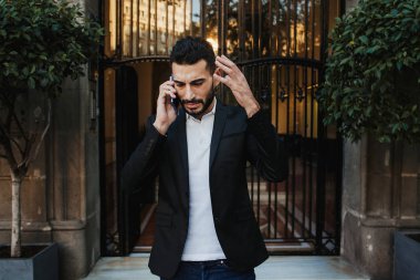 kızgın genç adam sokakta telefonda konuşuyor