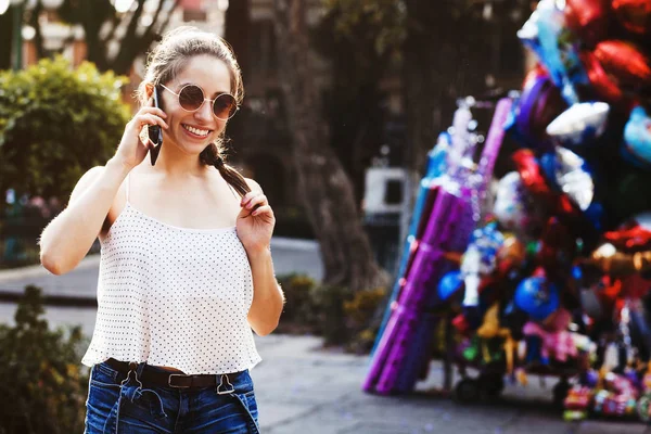 Retrato de chica latina riéndose, adolescente al aire libre en un teléfono inteligente en una ciudad colonial en México — Foto de Stock