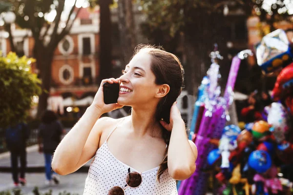 Retrato de chica latina riéndose, adolescente al aire libre en un teléfono inteligente en una ciudad colonial en México — Foto de Stock