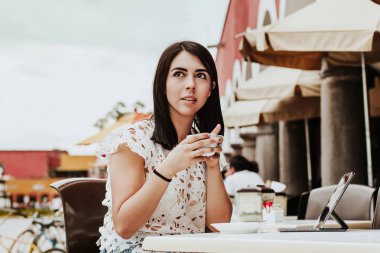 Meksika Meydanı'ndaki teras kafe restoranında oturan kadın bir fincan sıcak içecek çayı tutuyor. Mexico City genç Latin kadın