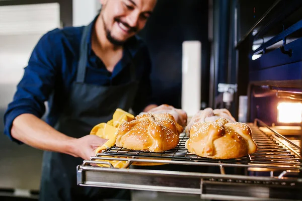 Mexican man baking bread called pan de muerto traditional from Mexico in Halloween