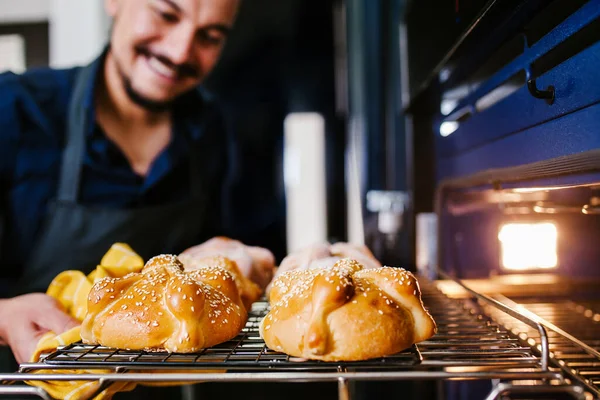 Mexican man baking bread called pan de muerto traditional from Mexico in Halloween