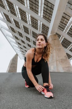 Latin Amerika 'da spor yapmak ya da dışarıda koşmak için ayakkabı bağcıklarını bağlayan genç İspanyol kadın.