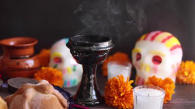 Latin Amerika 'da Meksika Ölüler Günü' nü kutlamak için sunakta şeker kafatası ve sıcak çikolata ile Meksika ekmeği ve tütsülenmiş tütsü.