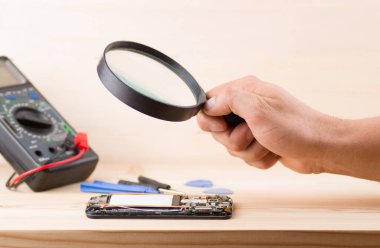 Teknisyen akıllı telefon konseptini tamir etmek için büyüteç kullanıyor. Cep telefonu, elektronik, tamirat.
