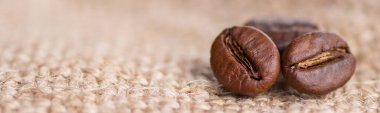 Kahverengi kavrulmuş kahve çekirdekleri çuval bezi arka planda siyah kafein içeceği ve enerji bileşeni.