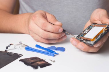 Tamirci, parçalanmış akıllı telefonu özel aletlerle tamir ediyor. Elektronik tamir cihazları kavramı