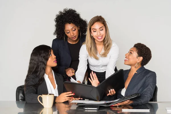 Group of four minority businesswomen working together in the office