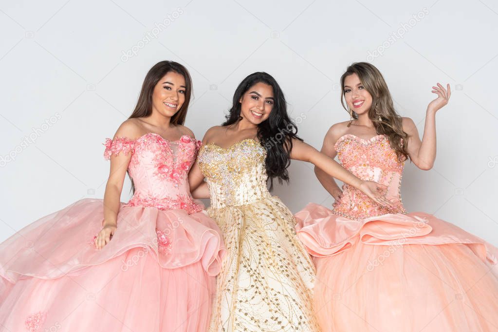 Group of three teenage hispanic girls wearing quinceanera dresses