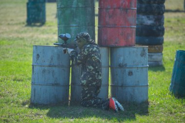 Paintball oyuncular kamuflaj üniforma ve koruyucu maske sahada, silahla ateş düşman yazın 