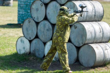 Paintball oyuncular kamuflaj üniforma ve koruyucu maske sahada, silahla ateş düşman yazın 
