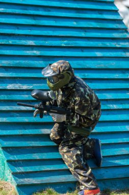 Paintball oyuncular kamuflaj üniforma ve koruyucu maske sahada, silahla ateş düşman yazın 