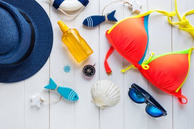 Yaz aksesuarları kadın için: hasır şapka, pusula, kabuklar, Mayo, Gözlük, güneş sprey, ahşap arka plan üzerinde balıklar. Seyahat, yaz satış konsepti