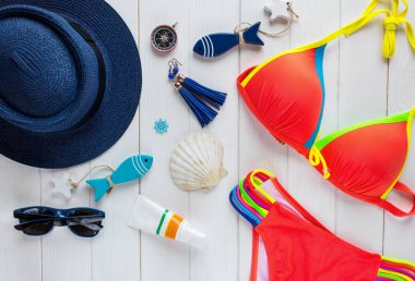 Yaz aksesuarları kadın için: hasır şapka, pusula, kabuklar, Mayo, Gözlük, güneş sprey, ahşap arka plan üzerinde balıklar. Seyahat, yaz satış konsepti