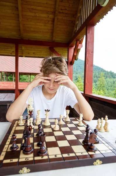 年轻的男孩正在考虑在棋盘上的移动 教育理念 象棋课 智力游戏 — 图库照片