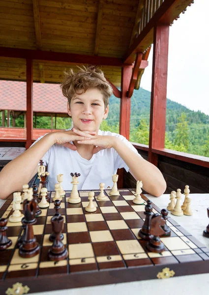 smart, cute, young boy is thinking about a move on the  chessboard.Education concept, chess lesson,  intellectual game