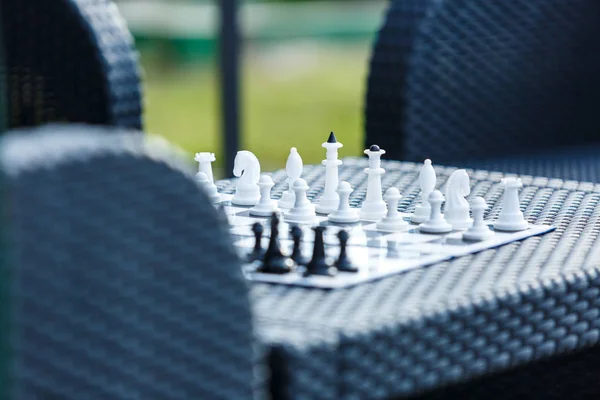 chessboard on the rattan table in the garden in the summer. Travel, vacation, holidays concept  Education concept, chess lesson, training, intellectual game