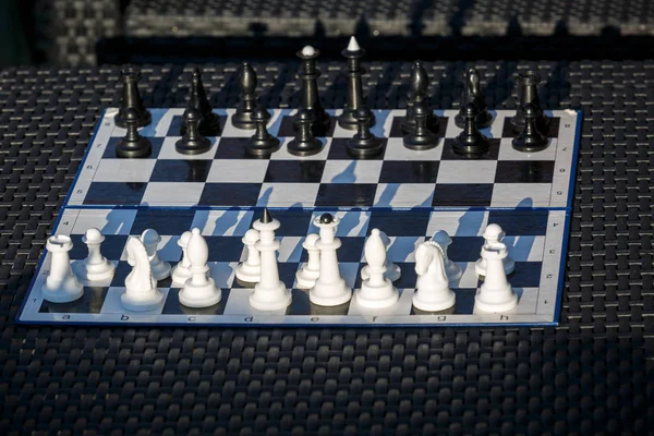 chessboard on the rattan table in the garden in the summer. Travel, vacation, holidays concept  Education concept, chess lesson, training, intellectual game