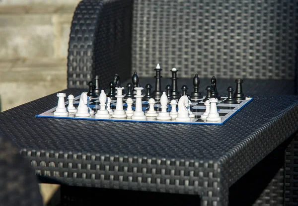 chessboard on the rattan table in the garden in the summer. Travel, vacation, holidays concept  Education concept, chess lesson, training, intellectual game