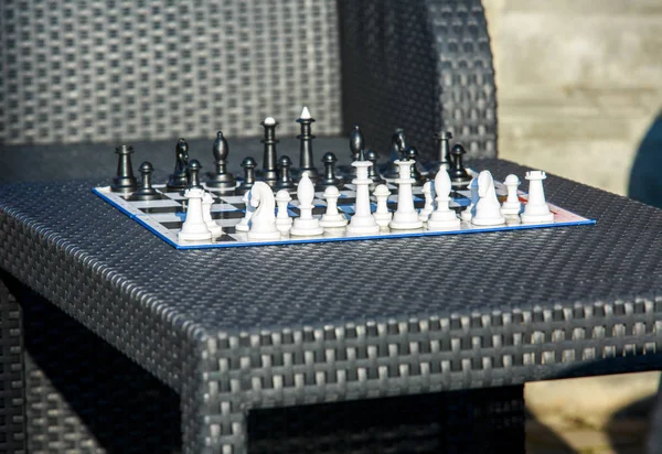 chessboard on the rattan table in the garden in the summer. Travel, vacation, holidays concept  Education concept, chess lesson, training, intellectual game