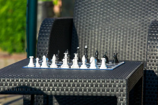 chessboard on the rattan table in the garden in the summer. Travel, vacation, holidays concept  Education concept, chess lesson, training, intellectual game