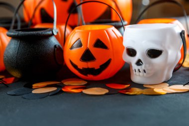Halloween süslemeleri. Dekoratif Turuncu kabak, kazanlarda, kafatasları siyah arka plan üzerine. Cadılar Bayramı kavramı. 