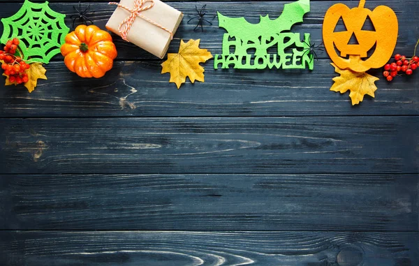 Halloween decor: leaves, rowan, pumpkins, banners on the wooden background. Halloween decorations. Flat lay, copyspace, top view