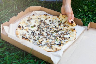 yaz parkta kutusundan dilim mantar ve peynir pizza oğlanın elini tutuyor.