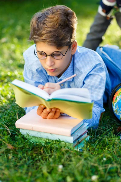 Roztomilý Mladý Chlapec Kulaté Brýle Modrou Košili Leží Trávě Čte — Stock fotografie