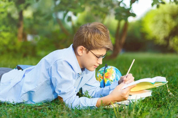 Roztomilý Mladý Chlapec Kulaté Brýle Modrou Košili Leží Trávě Čte — Stock fotografie