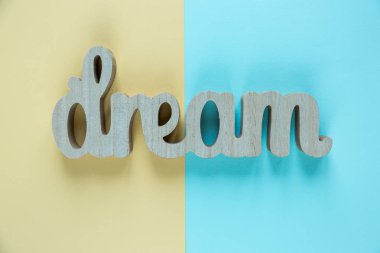 Word ahşap harflerin yapılan rüya mavi ve sarı arka plan üzerinde yatıyor. Motivasyon kelime. Düz lay, boşaltmak