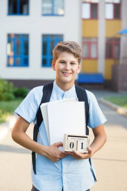 Sevimli, güzel, Genç 11 yaşında mavi gömlekli çocuk kitaplarıyla onun okulun önünde duruyor. Eğitim, okul kavramı başa