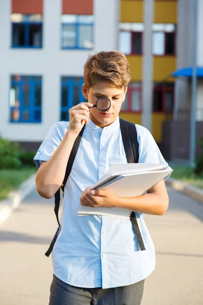 Søt Ung Skolegutt Blå Skjorte Med Ryggsekk Forstørrelsesglass Foran Skolen – stockfoto