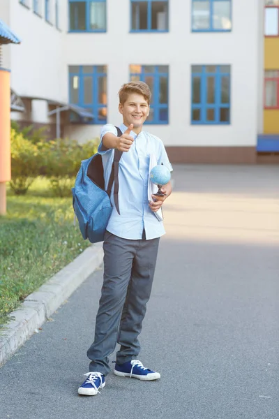 Cute Young Boy Blue Shirt Backpack Stands Front His School — Stock Photo, Image