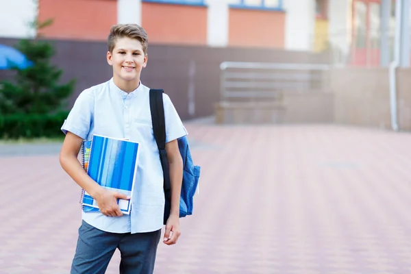 可爱的 漂亮的 年轻的11岁的男孩穿着蓝色衬衣站在他的学校前面的工作簿 回到学校概念 — 图库照片