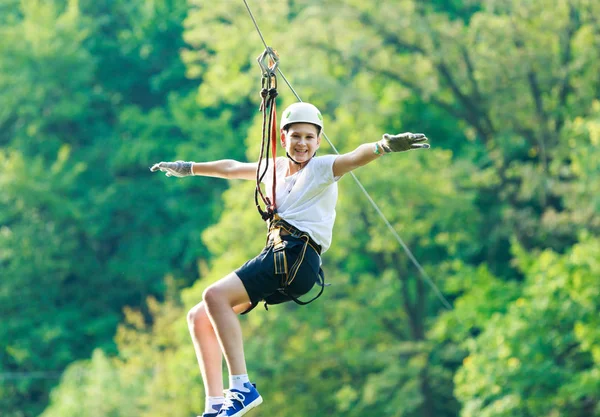 şirin, sportif çocuk kask ve güvenlik ekipmanları ile macera ip etkinlik parkta Beyaz tişörtlü. Genç çocuk oynamaya ve sahip eğlenceli aktiviteler açık havada yaptığını. Hobi, aktif yaşam tarzı kavramı