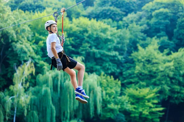 Beyaz t gömlek ve beyaz kask kask ve güvenlik ekipmanları ile macera ip etkinlik parkta sportif, tatlı çocuk. Genç çocuk oynamaya ve sahip eğlenceli aktiviteler açık havada yaptığını. Hobi, aktif yaşam tarzı kavramı
