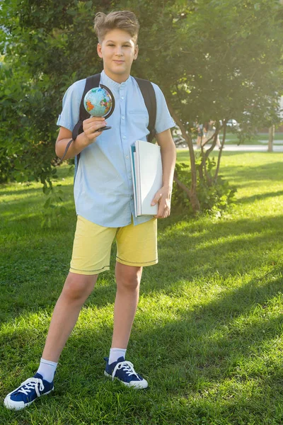 可爱的小男孩穿着蓝色衬衣在夏天在公园里抱着地球仪和笔记本 回到学校 教育理念 — 图库照片