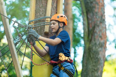 Eğleniyor ve Macera Parkı'nda oynarken, ipleri tutan ve ahşap merdiven çıkma mavi t gömlek ve turuncu kask mutlu, Sevimli, Genç çocuk. aktif yaşam tarzı kavramı
