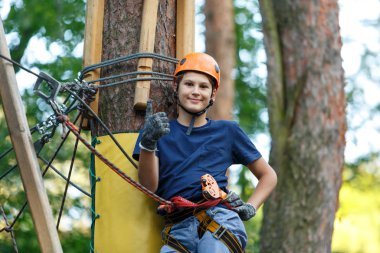 Eğleniyor ve Macera Parkı'nda oynarken, ipleri tutan ve ahşap merdiven çıkma mavi t gömlek ve turuncu kask mutlu, Sevimli, Genç çocuk. aktif yaşam tarzı kavramı
