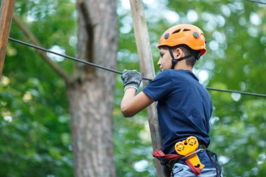 Eğleniyor ve Macera Parkı'nda oynarken, ipleri tutan ve ahşap merdiven çıkma mavi t gömlek ve turuncu kask mutlu, Sevimli, Genç çocuk. aktif yaşam tarzı kavramı