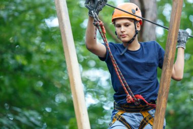 Eğleniyor ve Macera Parkı'nda oynarken, ipleri tutan ve ahşap merdiven çıkma mavi t gömlek ve turuncu kask mutlu, Sevimli, Genç çocuk. aktif yaşam tarzı kavramı