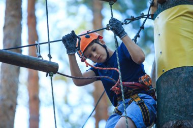 Eğleniyor ve Macera Parkı'nda oynarken, ipleri tutan ve ahşap merdiven çıkma mavi t gömlek ve turuncu kask mutlu, Sevimli, Genç çocuk. aktif yaşam tarzı kavramı