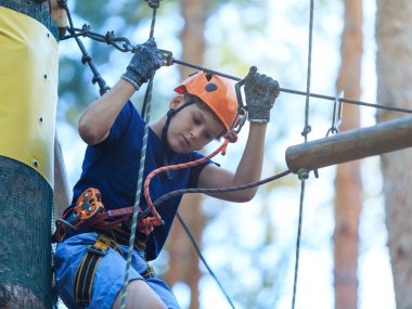 Eğleniyor ve Macera Parkı'nda oynarken, ipleri tutan ve ahşap merdiven çıkma mavi t gömlek ve turuncu kask mutlu, Sevimli, Genç çocuk. aktif yaşam tarzı kavramı