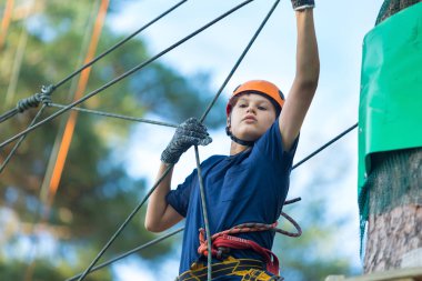 Eğleniyor ve Macera Parkı'nda oynarken, ipleri tutan ve ahşap merdiven çıkma mavi t gömlek ve turuncu kask mutlu, Sevimli, Genç çocuk. aktif yaşam tarzı kavramı
