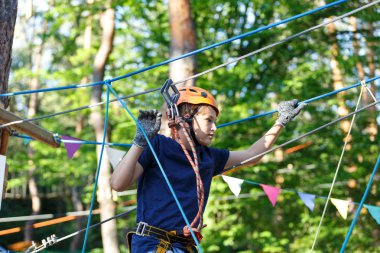 Mavi t gömlek ve eğleniyor ve Macera Parkı'nda oynarken, ipleri tutan ve ahşap merdiven çıkma kask mutlu, Sevimli, Genç çocuk. aktif yaşam tarzı kavramı