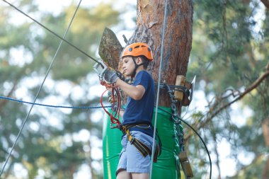 Mavi t gömlek ve eğleniyor ve Macera Parkı'nda oynarken, ipleri tutan ve ahşap merdiven çıkma kask mutlu, Sevimli, Genç çocuk. aktif yaşam tarzı kavramı