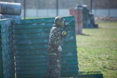 Kamuflaj elbiseli çocuk onun paintball silahı ile paintball sahada duruyor ve dümdüz görünüyor. takım çalışması, spor yaşam tarzı