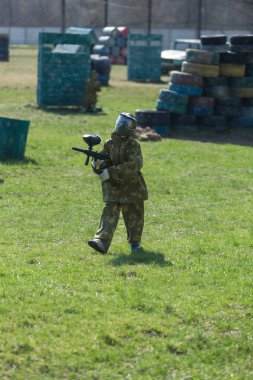 Kamuflaj elbiseli çocuk onun paintball silahı ile paintball sahada duruyor ve dümdüz görünüyor. takım çalışması, spor yaşam tarzı
